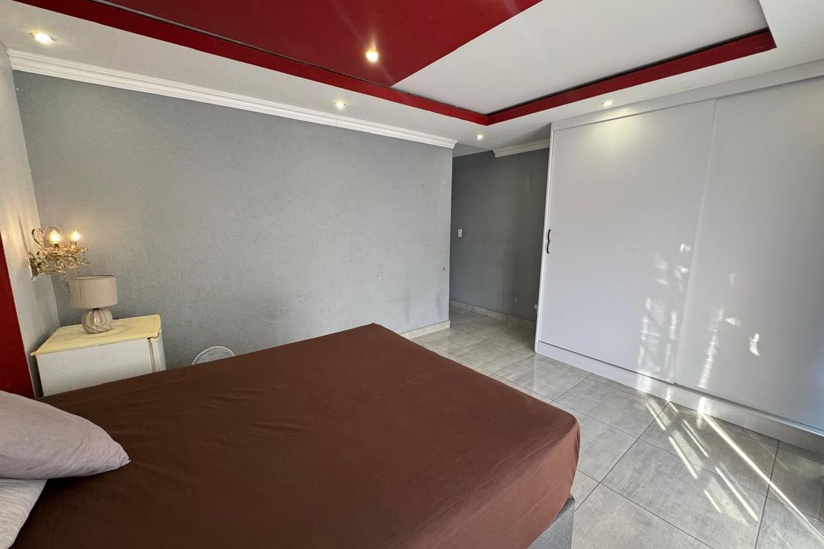Bedroom featuring tiled flooring, built-in sliding door wardrobe, and a decorative recessed ceiling with integrated lighting.