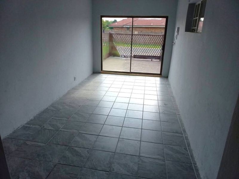 An empty, tiled living area featuring a sliding glass door that provides access to the exterior.