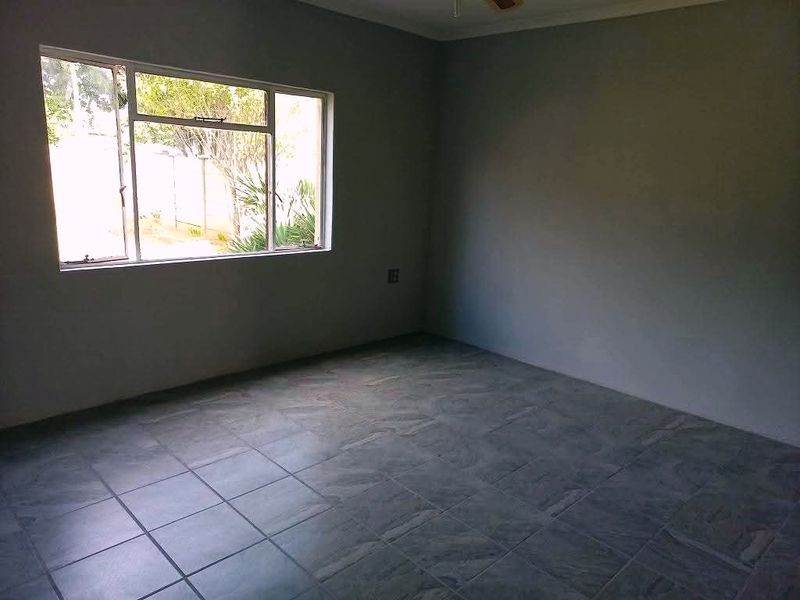 A spacious, empty bedroom featuring neutral grey walls and durable tiled flooring, offering a blank canvas for personalization.