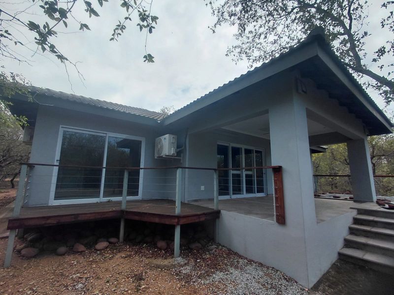Rear exterior view of the house featuring a covered patio, timber decking, sliding glass doors, and an installed air conditioning unit.