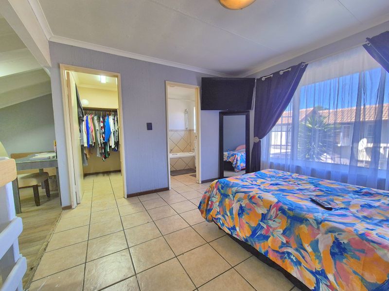 Spacious bedroom featuring tiled flooring, an integrated walk-in closet, and an en-suite bathroom, offering a functional layout with natural light.