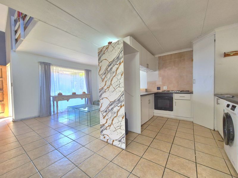 Open-plan living area featuring a functional kitchen with built-in oven, gas hob, and tiled flooring throughout the combined space.