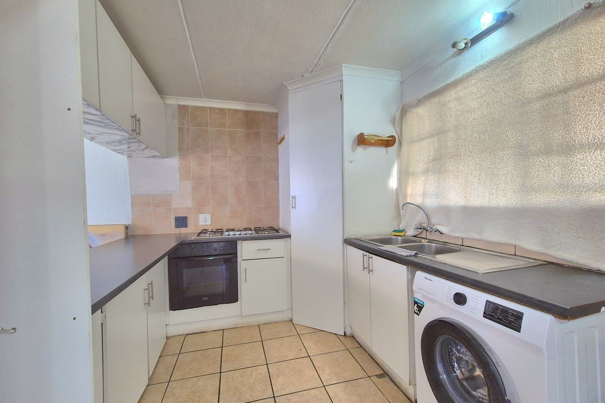 Functional kitchen featuring built-in cabinetry, gas hob, oven, double sink, and tiled flooring, offering a practical layout with ample storage space.