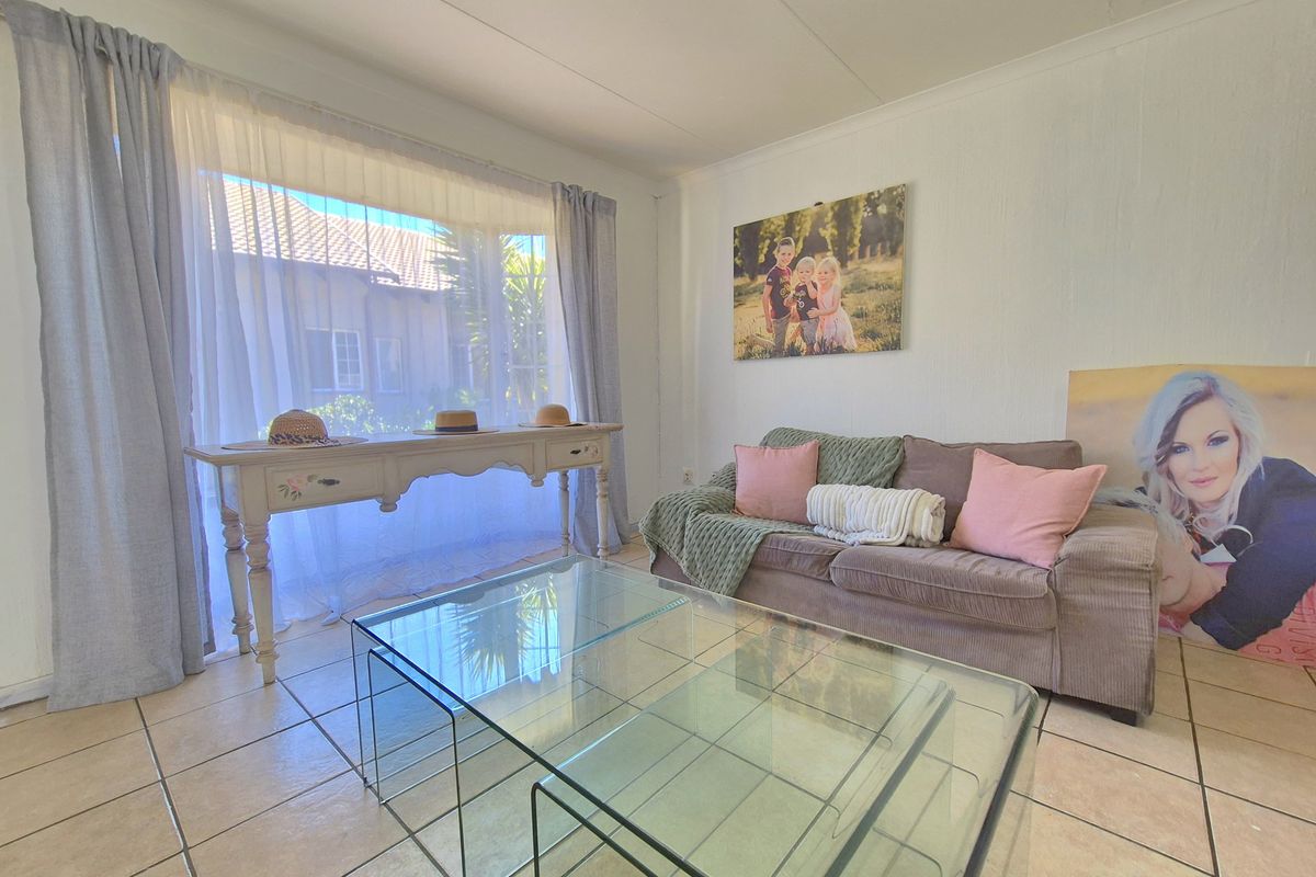 A bright living room featuring neutral tiled flooring and a large window that allows for ample natural light.