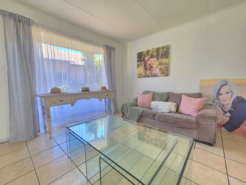A bright living room featuring neutral tiled flooring and a large window that allows for ample natural light.