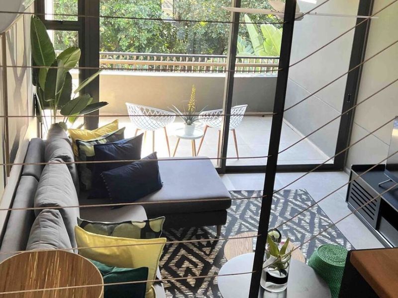 Modern living room featuring large sliding glass doors that open onto a private balcony, complemented by tiled flooring and integrated air conditioning.