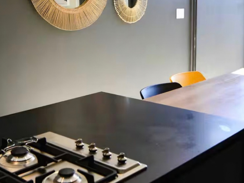 Modern open-plan living area featuring a sleek kitchen island with an integrated gas hob and direct access to an outdoor space.