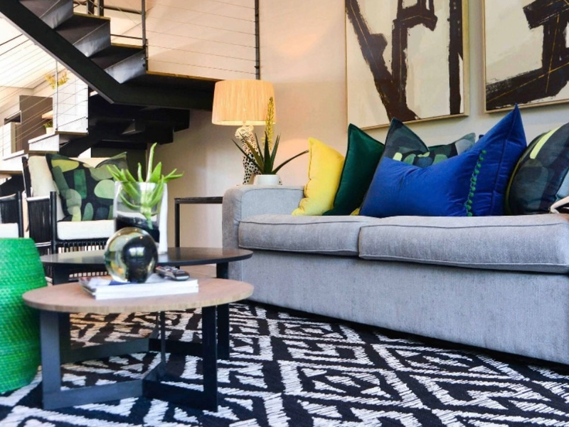 A modern living room featuring a striking black metal staircase with cable railings, creating an open and contemporary architectural aesthetic.
