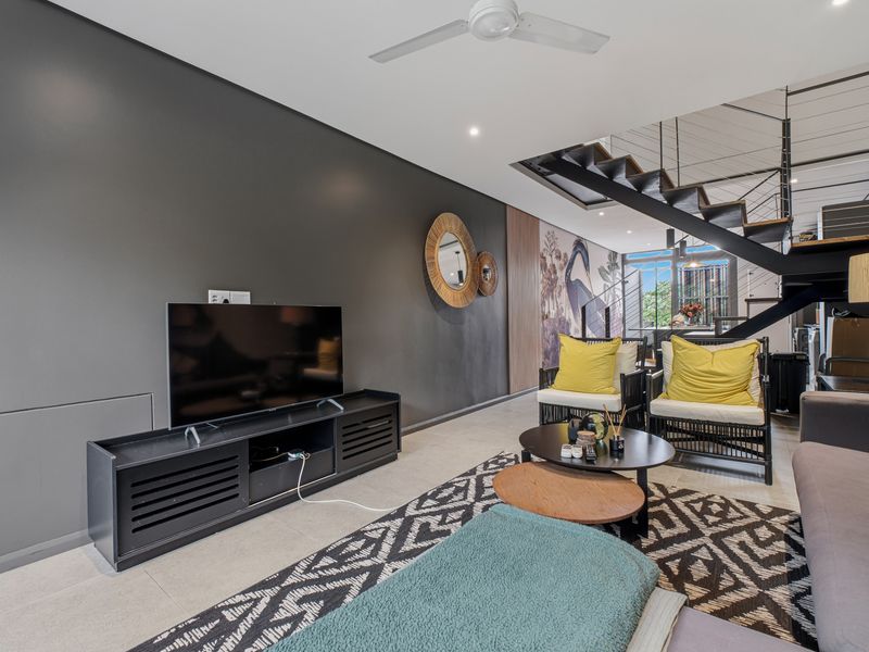 Modern open-plan living area featuring tiled flooring, recessed lighting, a ceiling fan, and a striking staircase with metal railings.