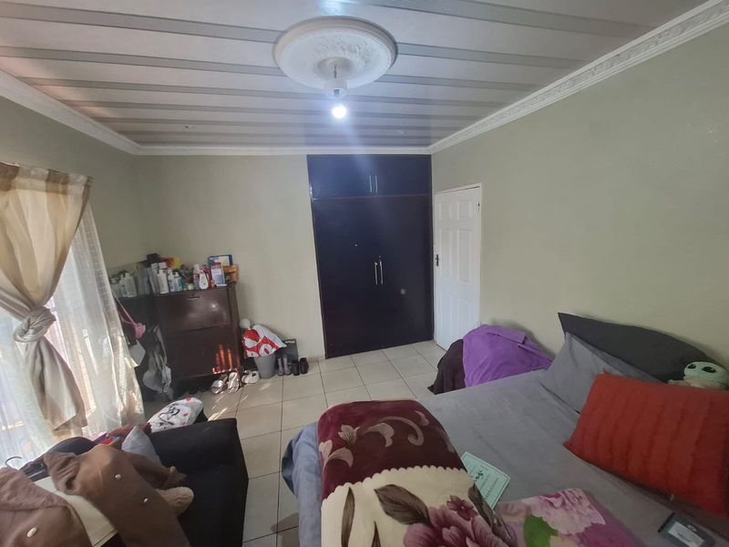 A bedroom featuring tiled flooring, a built-in wardrobe, and decorative ceiling cornicing with a central ceiling rose.