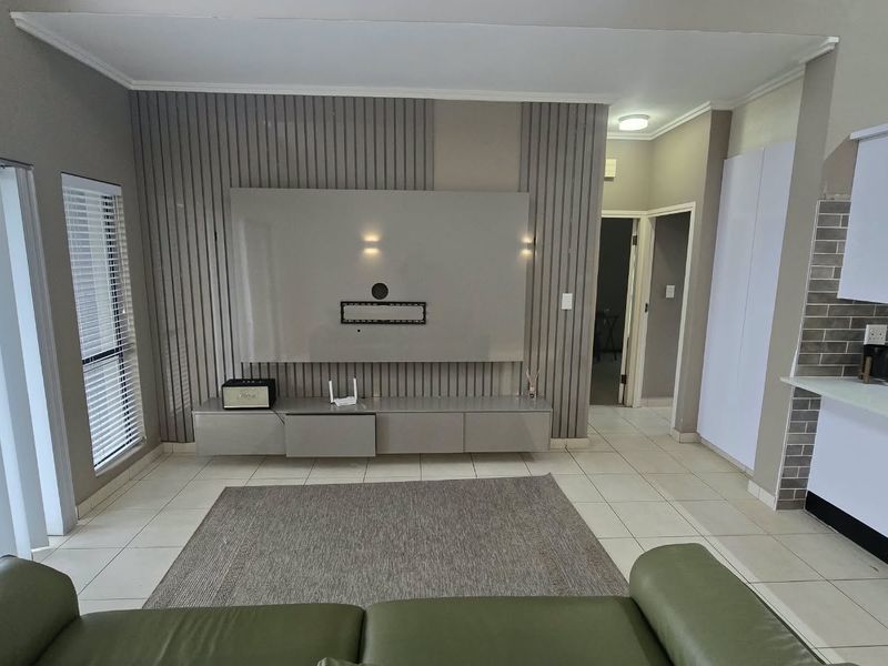 Modern open-plan living area featuring a stylish slatted wood feature wall, built-in media console, and a sleek kitchen with quartz countertops and subway tile backsplash.