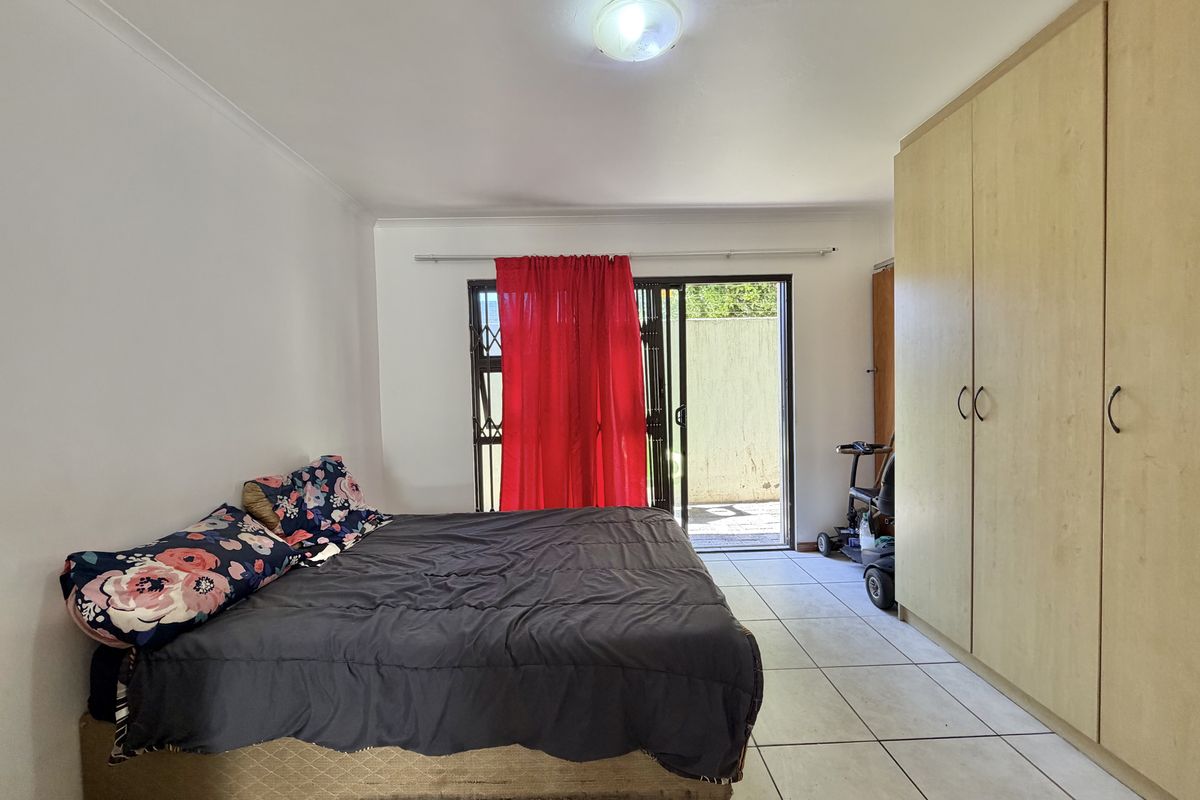 Spacious bedroom featuring built-in cupboards, tiled flooring, and a sliding glass door providing direct access to the outdoor area.