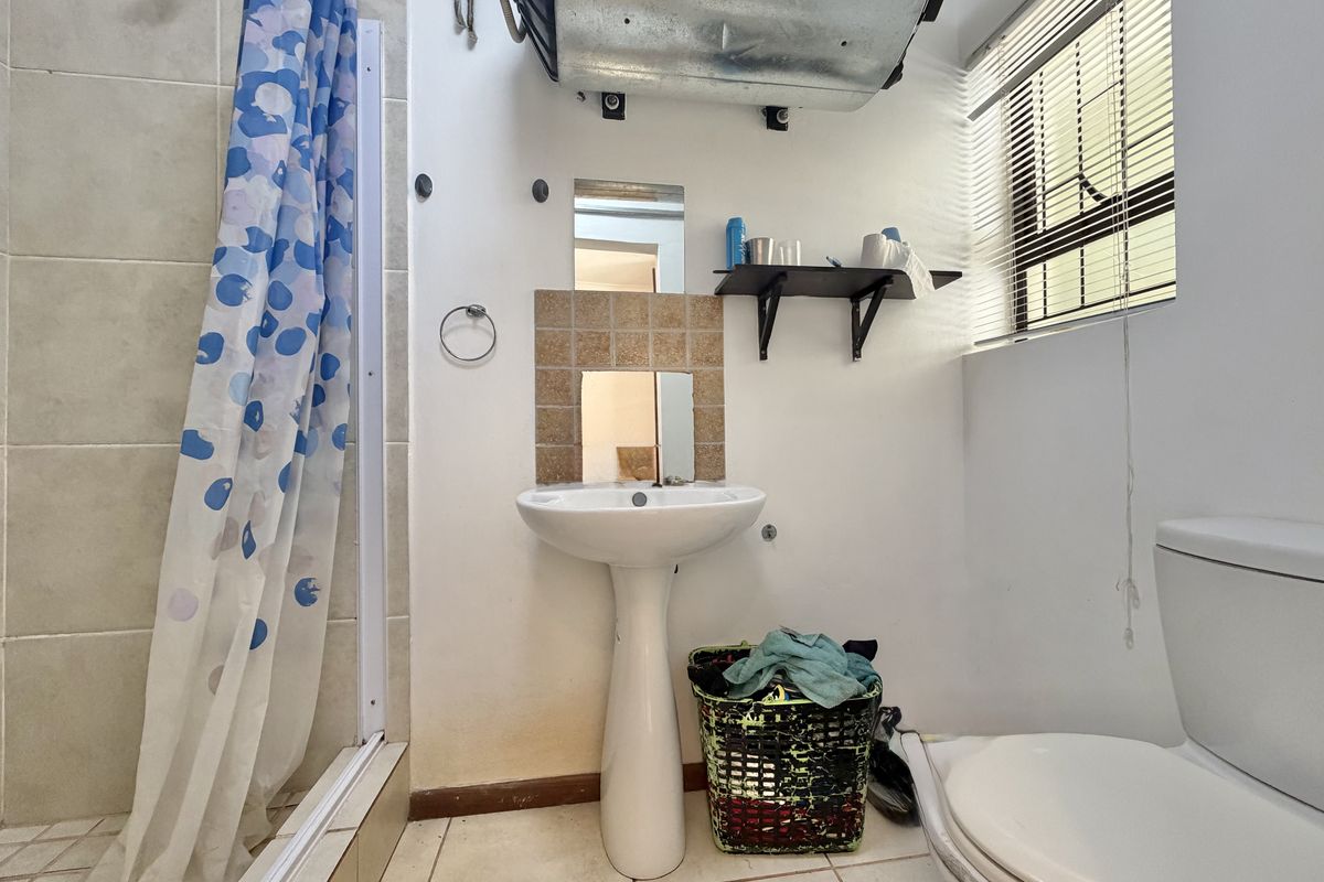 Compact bathroom featuring a pedestal basin, shower enclosure, and toilet. The space requires cosmetic updates and improved finishings to enhance its overall appeal.