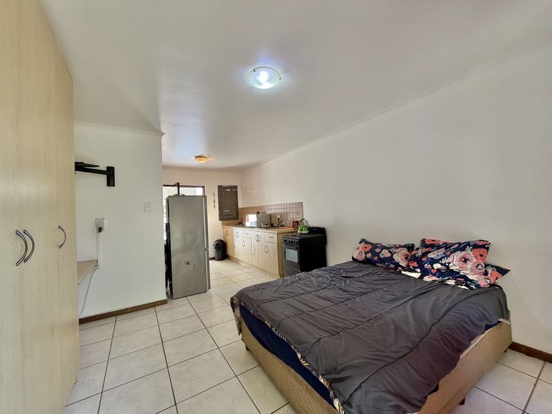 Open-plan studio apartment featuring a combined bedroom and kitchen area with tiled flooring and built-in cabinetry.