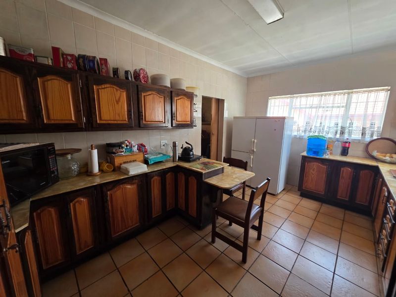 A functional kitchen featuring traditional wooden cabinetry, tiled flooring, and ample counter space, offering potential for a modern renovation.