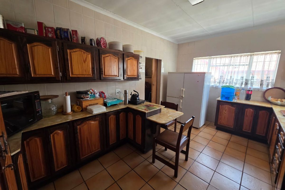 A functional kitchen featuring traditional wooden cabinetry, tiled flooring, and ample counter space, offering potential for a modern renovation.