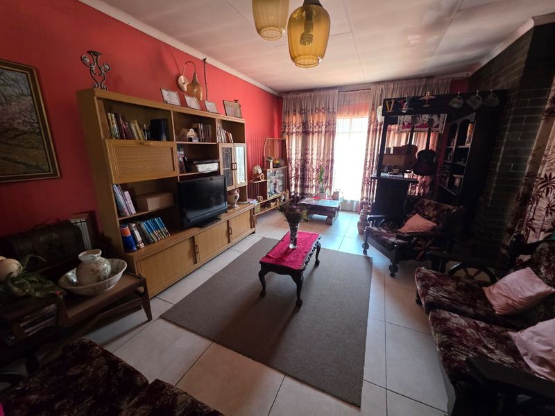 A living room featuring tiled flooring and a brick fireplace, currently showing dated finishes and signs of wear.