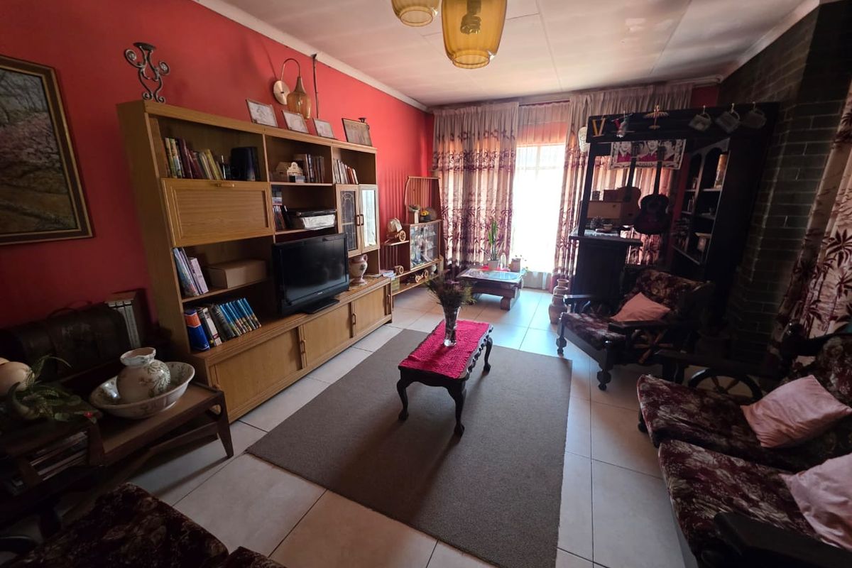 A living room featuring tiled flooring and a brick fireplace, currently showing dated finishes and signs of wear.