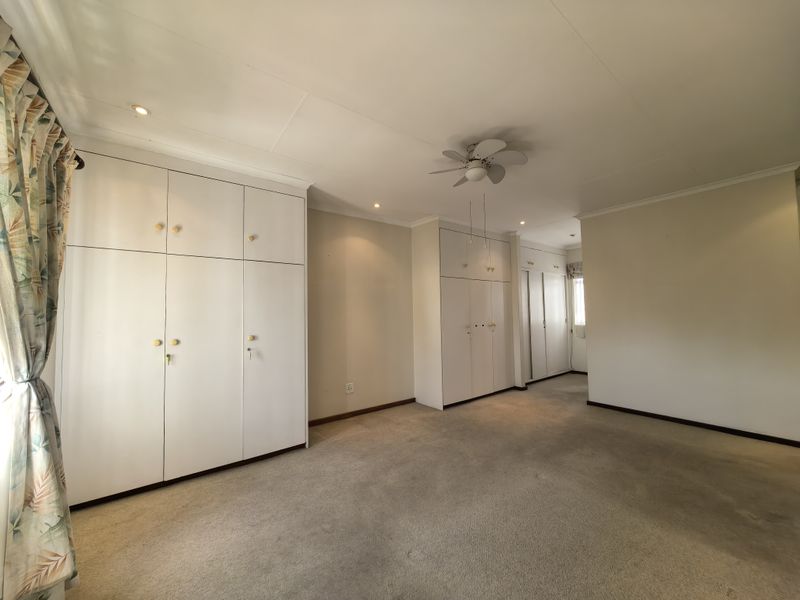 Spacious bedroom featuring extensive built-in cupboard storage, a ceiling fan, recessed lighting, and neutral carpeting throughout.