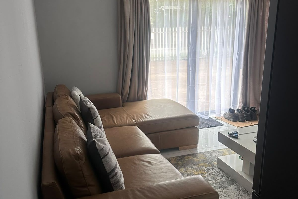 A comfortable living room featuring tiled flooring, modern track lighting, and a large sliding glass door providing access to the outdoor area.