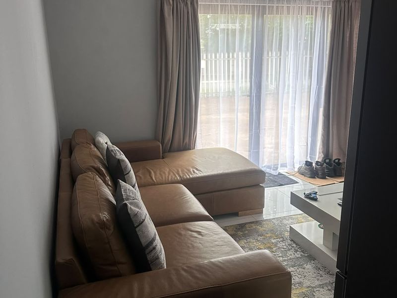 A comfortable living room featuring tiled flooring, modern track lighting, and a large sliding glass door providing access to the outdoor area.