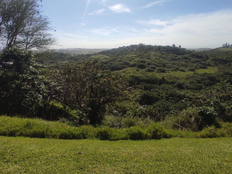 A scenic view overlooking a lush green valley and rolling hills, showcasing the natural landscape surrounding the property.