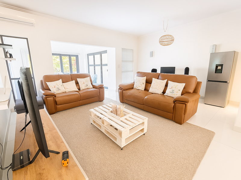 Bright and spacious living area featuring tiled flooring, split-system air conditioning, and large aluminium sliding doors leading to an outdoor space.