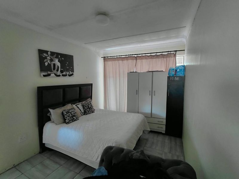 A bedroom featuring tiled flooring and a ceiling light fixture, requiring minor cosmetic updates to the walls and ceiling.