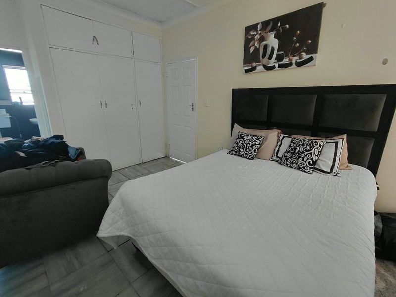 A bedroom featuring built-in cupboards, tiled flooring, and a standard panel door, providing a functional and neutral living space.