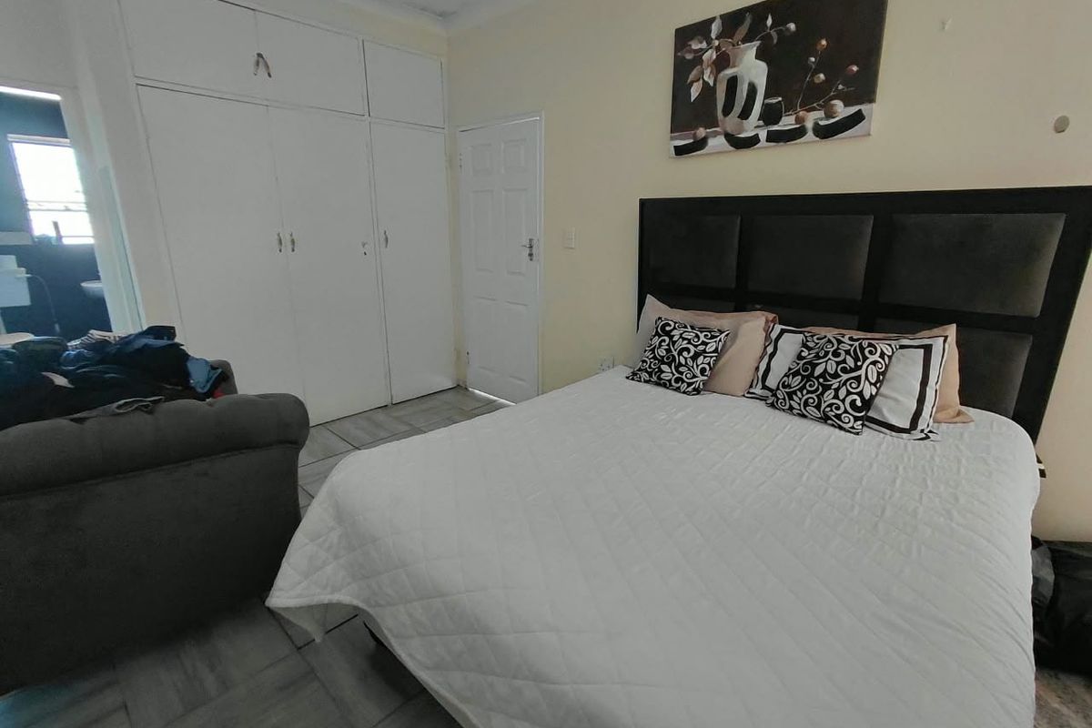 A bedroom featuring built-in cupboards, tiled flooring, and a standard panel door, providing a functional and neutral living space.
