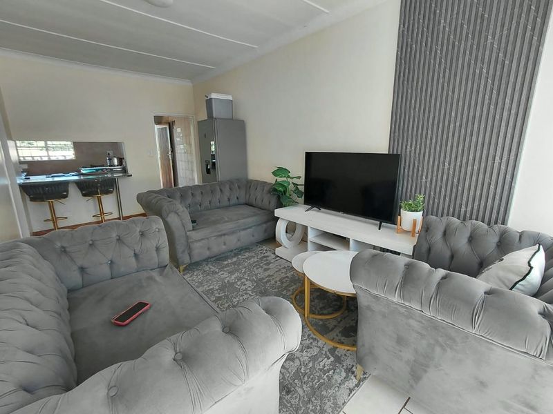 Open plan living area featuring decorative wall paneling, tiled flooring, and a breakfast bar connecting to the kitchen space.