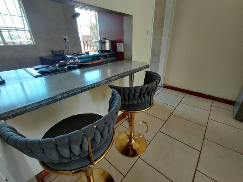 Kitchen area featuring a breakfast bar with granite countertop, built-in hob, and tiled flooring.