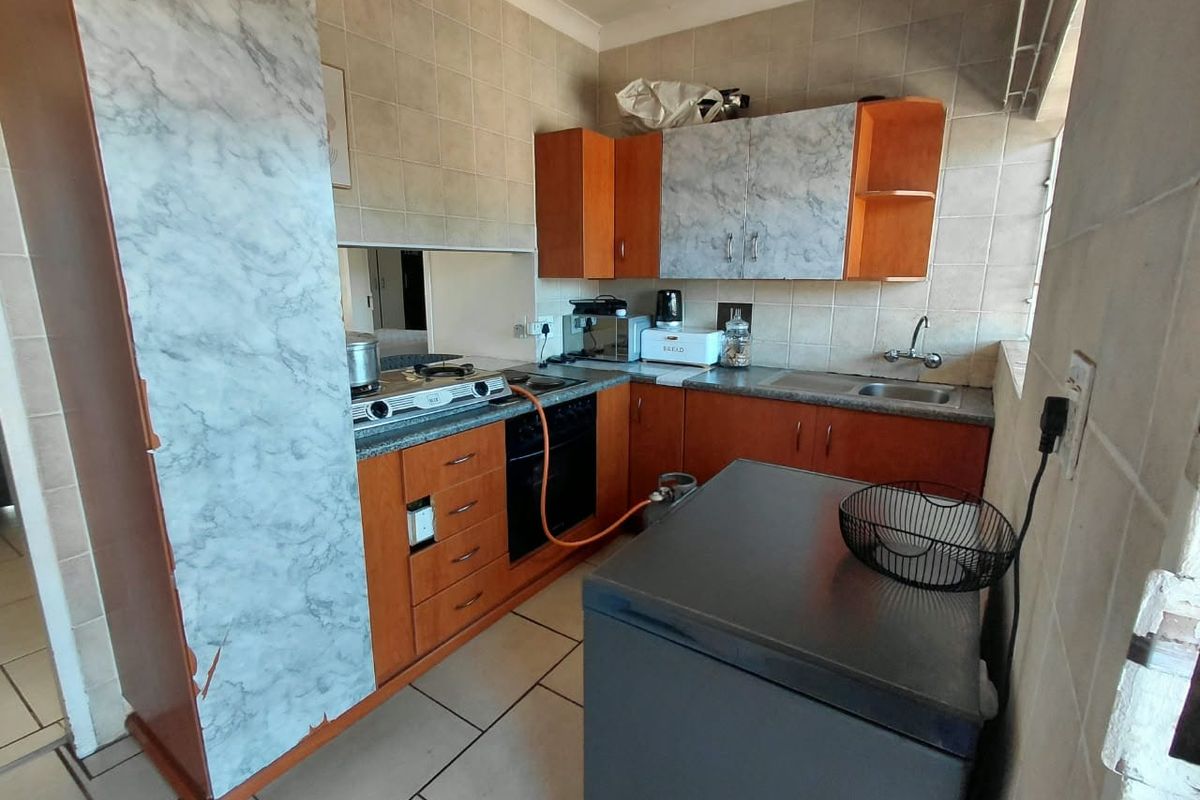 Compact kitchen featuring built-in cabinetry, tiled backsplash, gas hob, and oven. The space offers functional storage and preparation areas with a classic layout.