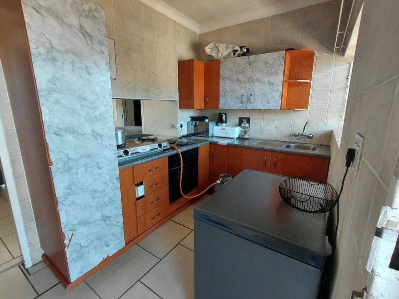 Compact kitchen featuring built-in cabinetry, tiled backsplash, gas hob, and oven. The space offers functional storage and preparation areas with a classic layout.