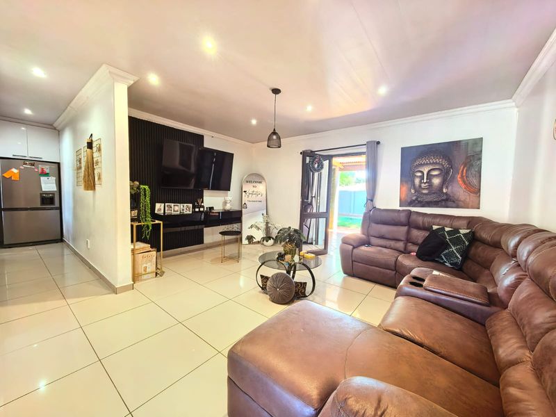 Open plan living area featuring tiled flooring, recessed lighting, and a modern slatted feature wall, with direct access to the outdoor patio.