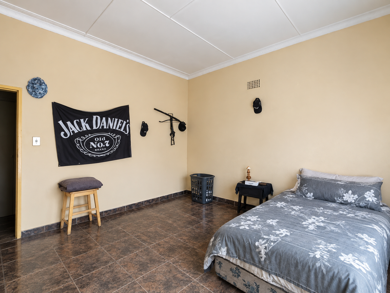 A bedroom featuring tiled flooring and ceiling cornice detailing, providing a functional space with neutral wall finishes.