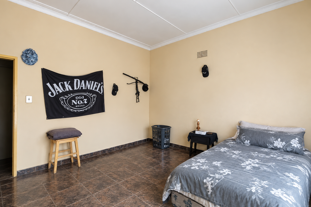 A bedroom featuring tiled flooring and ceiling cornice detailing, providing a functional space with neutral wall finishes.
