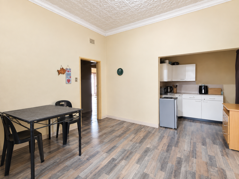 Open plan living area featuring a compact kitchen nook, pressed metal ceiling details, and durable laminate flooring throughout.