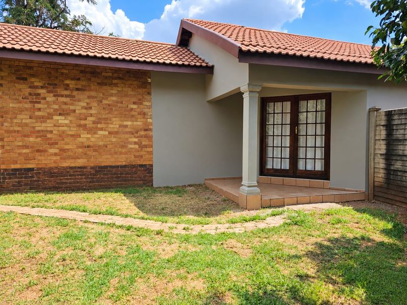 Rear view of the property featuring a covered patio with a fluted column, french doors, and a combination of facebrick and plastered exterior walls.