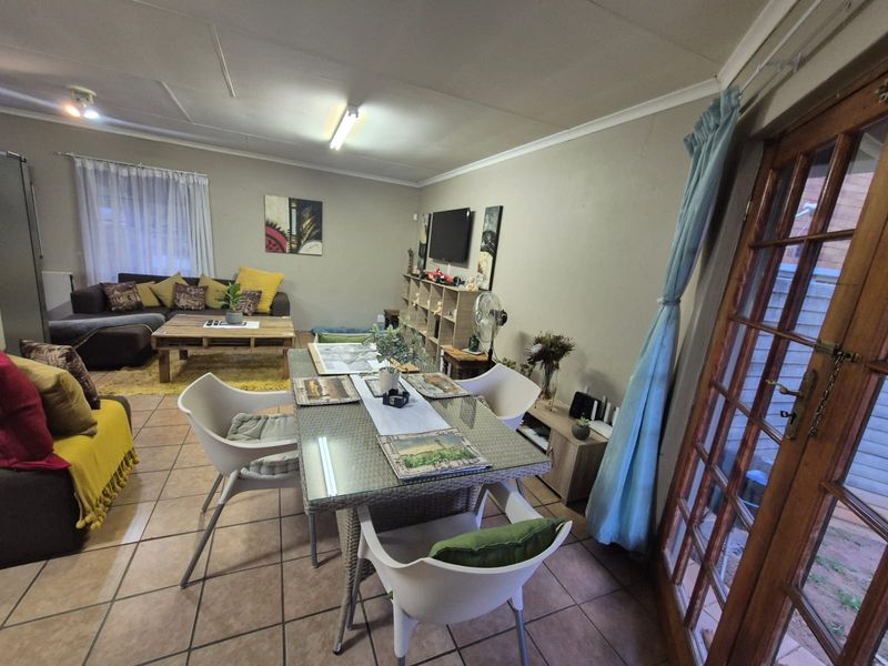 Open plan living and dining area featuring tiled flooring and a timber framed glass door leading to the exterior.