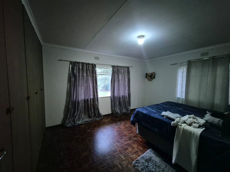 A spacious bedroom featuring classic parquet flooring and extensive built-in cupboard storage, offering a solid foundation for modern interior updates.