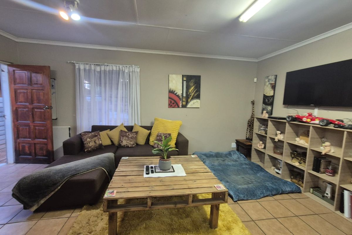 A living room featuring tiled flooring, a timber panel door, and coved ceilings, providing a functional and lived-in space.