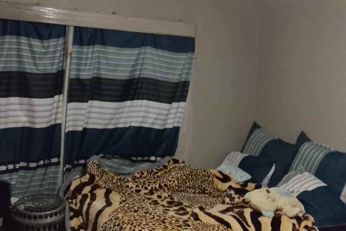 A bedroom featuring tiled flooring and a basic ceiling light fixture, currently showing signs of wear and requiring maintenance to the ceiling and walls.