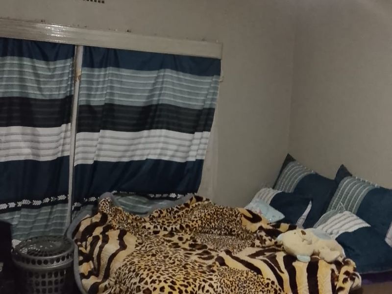 A bedroom featuring tiled flooring and a basic ceiling light fixture, currently showing signs of wear and requiring maintenance to the ceiling and walls.