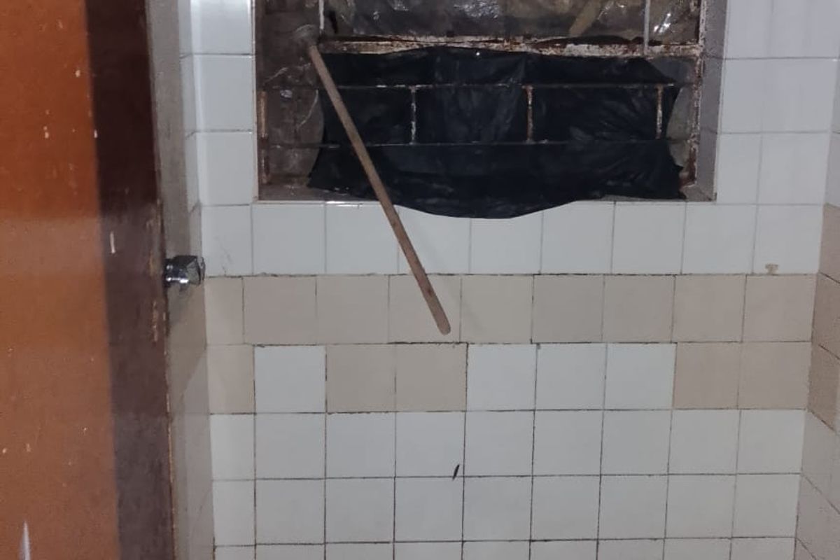 A basic shower area featuring tiled walls and flooring, currently in need of significant maintenance and repair to the window and wall finishes.