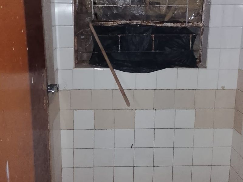A basic shower area featuring tiled walls and flooring, currently in need of significant maintenance and repair to the window and wall finishes.