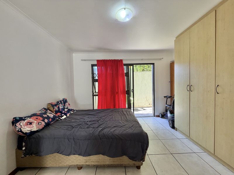 A bedroom featuring built-in cupboards, tiled flooring, and a sliding glass door providing access to an outdoor area.