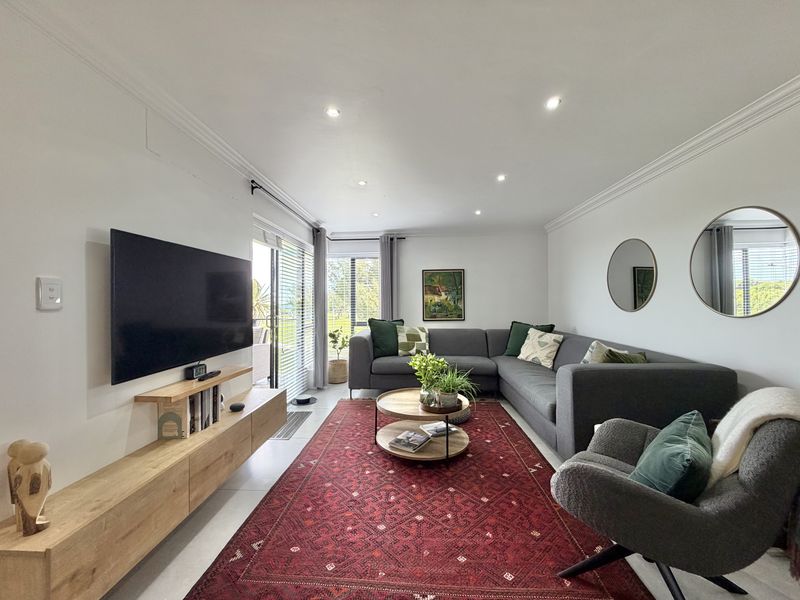 A bright and well-maintained living room featuring recessed downlighting, crown molding, tiled floors, and a sliding glass door providing access to the outdoors.