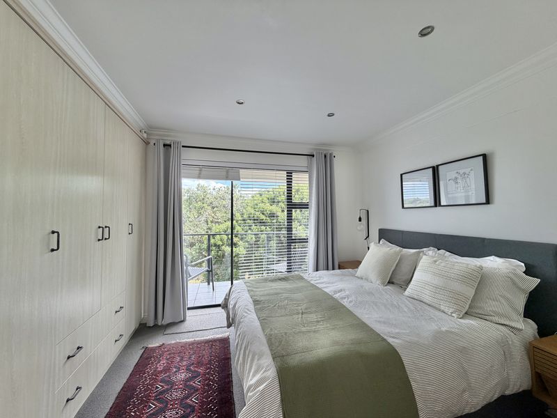A well-maintained bedroom featuring built-in cupboards, recessed lighting, and direct access to a private balcony through a sliding glass door.