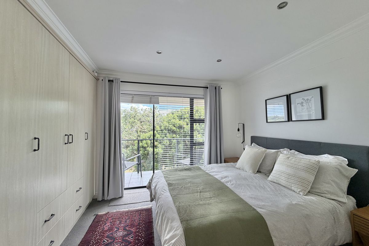 A well-maintained bedroom featuring built-in cupboards, recessed lighting, and direct access to a private balcony through a sliding glass door.